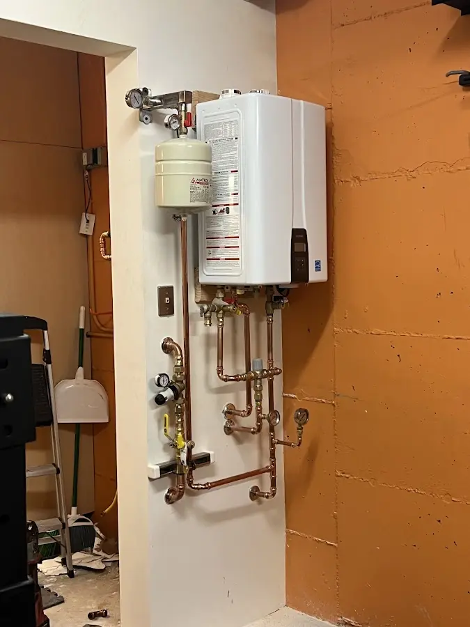Plumbing technician inspecting water heater connections in West Newbury